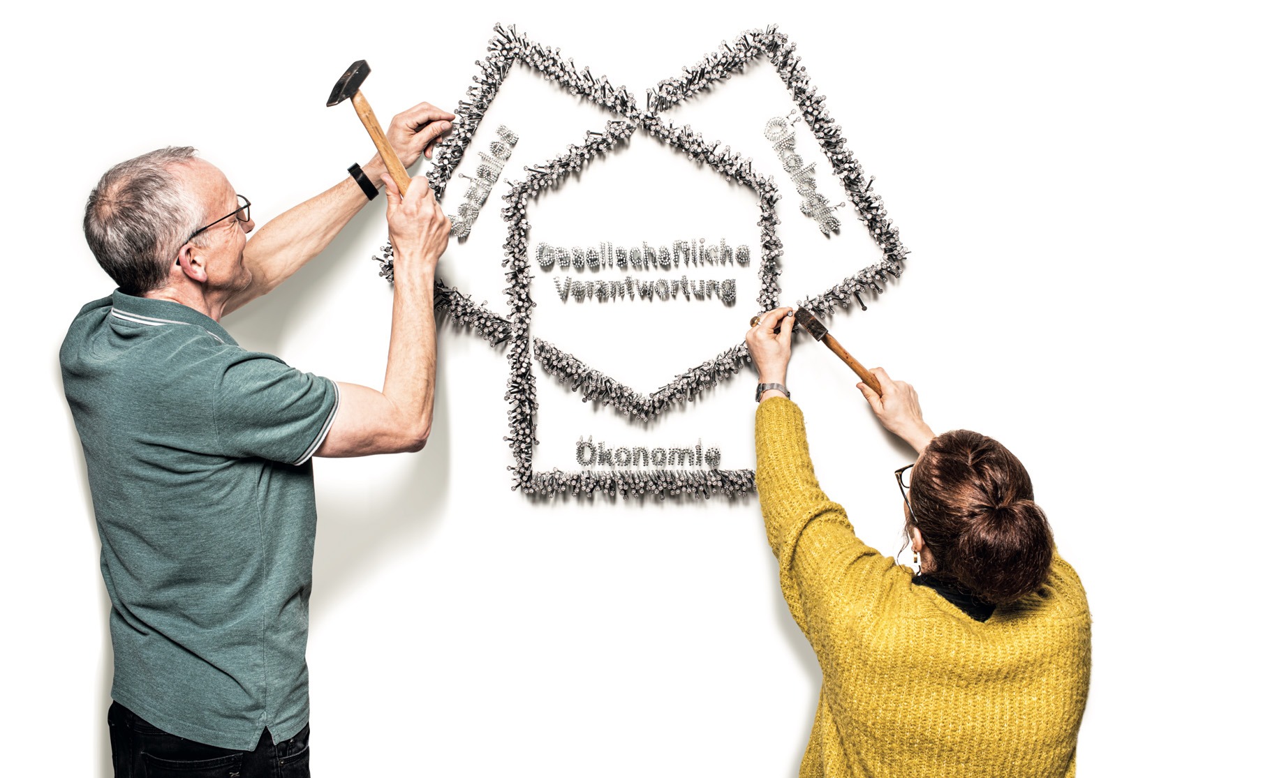 Bild von zwei Personen, die das Geschäftsmodell der GEWOBA an die Wand nageln.