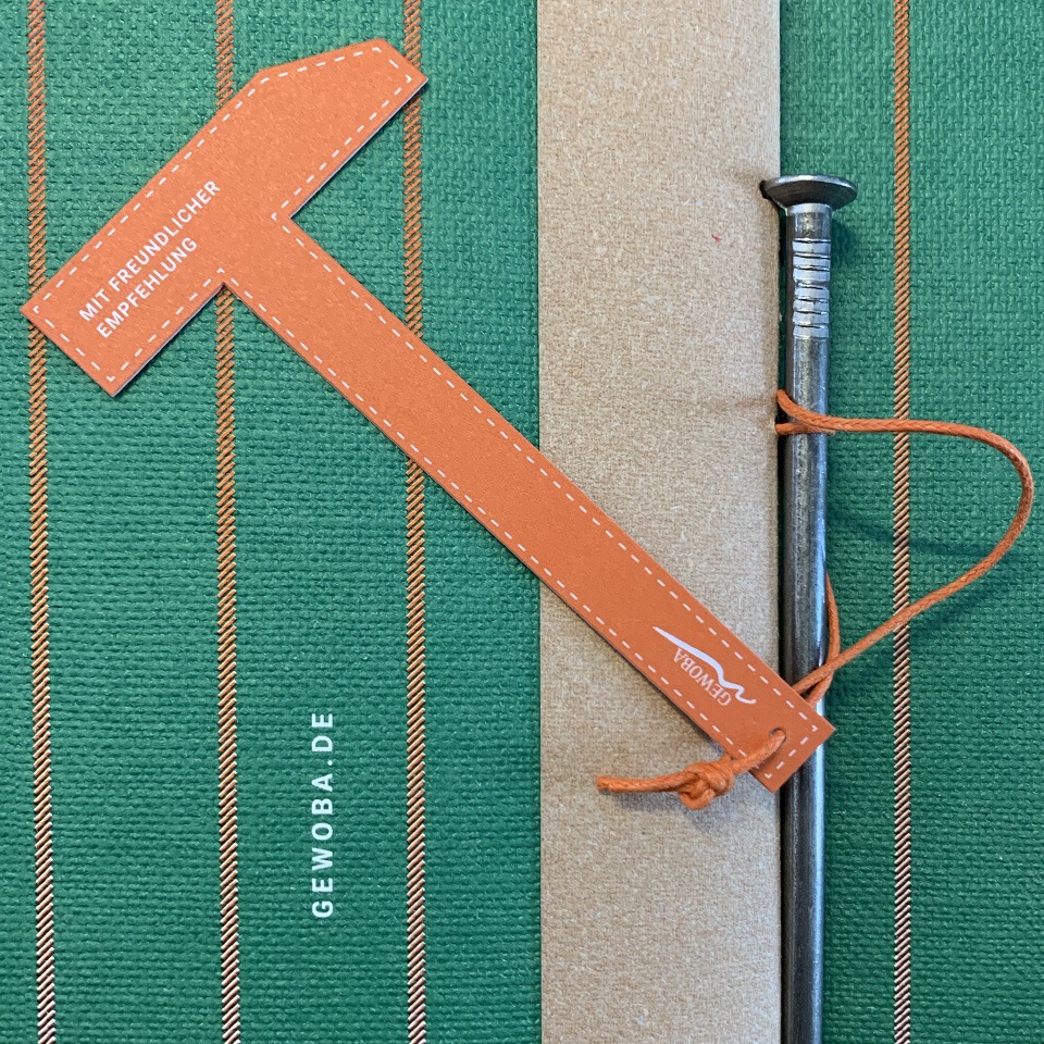 Detailaufnahmen des Zimmermannsnagel, sowie der orangen Grußkarte in Form eines Hammers.